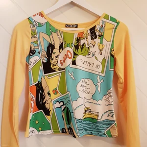  - Jättefin, annorlunda tröja från Coco girls. Står ingen storlek men är gissningsvis strlk S. Tryck på framsida i serietidningsstuk med gula ärmar och rygg. Knappt använd.  Frakt tillkommer