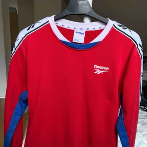  - Reebok tröja i röd med vita och blåa detaljer. använd en gång och sitter väldigt bra. den har även fickor på magen 