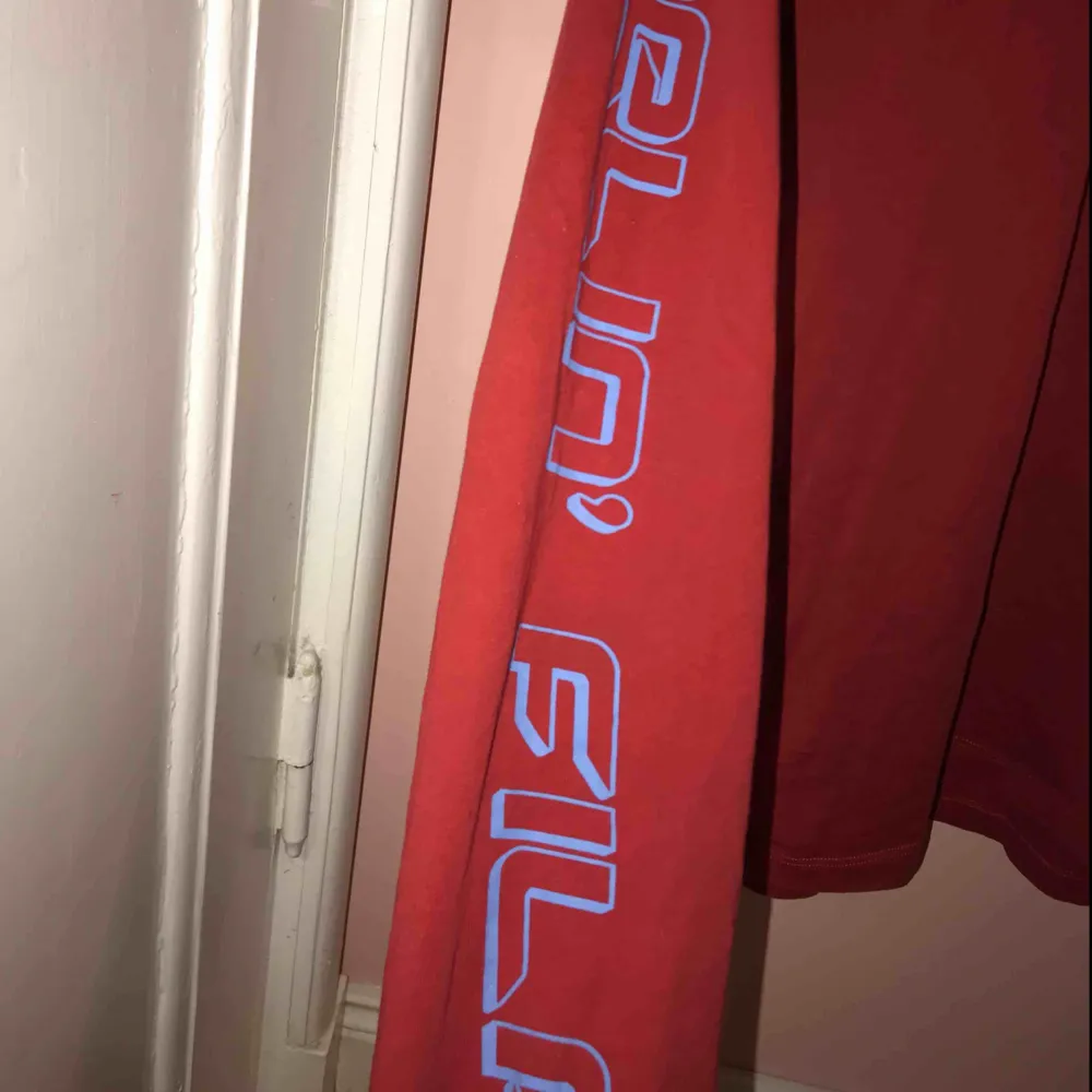 En röd tröja från FILA x JUNKYARD med rutor på ena ärmen och texten ” feelin’ fila” på den andra. Den är lite oversize på mig som vanligtvis har S. ( köparen står för frakt ) . Tröjor & Koftor.