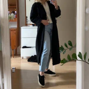 Lång svart kappa - Fin kappa i storlek S, går ner till smalbenen på mig som är 160 (se andra bilden). Säljer den då den inte kommer till användning💓💓 Frakt tillkommer