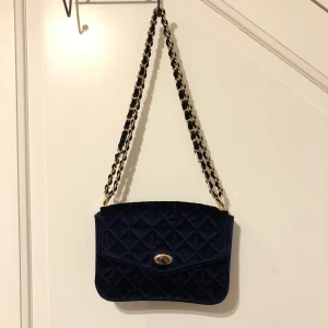 Sammet väska  - Säljer denna snygga väska som tyvärr inte kommit till någon användning. Mörkblå sammet med guld detaljer. 