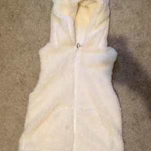 Vit fluffig väst - Säljer denna vita och fluffiga västen. Har aldrig använt den och den har en söt luva. Den är inte heller för tjock och har två fickor.  BUDA!!