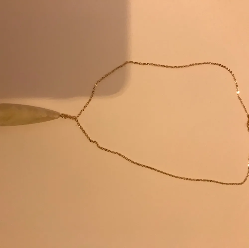 Ett guld halsband med en vit Sten . Accessoarer.