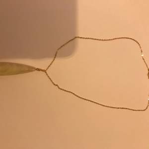 Ett guld halsband med en vit Sten 