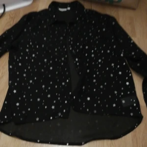 En blus  - En svart blus med krage och stjärnor från Kappahl storlek 152