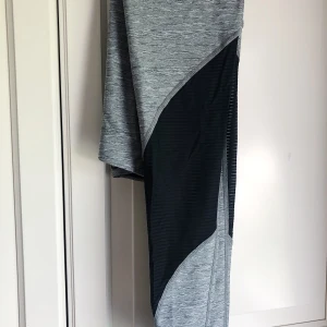 NIKE PRO-tights strl XS - Gråmelerade träningstights med resår i midjan och svarta mesh-detaljer kring vaderna från NIKE PRO. Storlek XS, men passar även S. Använda endast en gång.