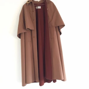  - Jättefin cape med pellerin från Hettemarks. Yttertyget är ljust nougatbrunt och fodret är mer rostbrunt. Ganska stor storlek, L kanske - sitter nog snyggast på någon som är lite längre. Väldigt gott skick och fina detaljer. 