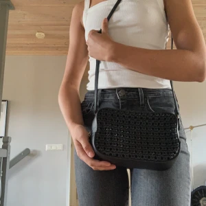 Svart axelremsväska med flätad detalj - Går att justera axelrämmen. Sparsamt använd. Priset är inkl frakt