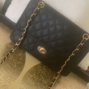 En helt vanlig väska men fin  - En svart skinnväska men guld kedjor som handtag 