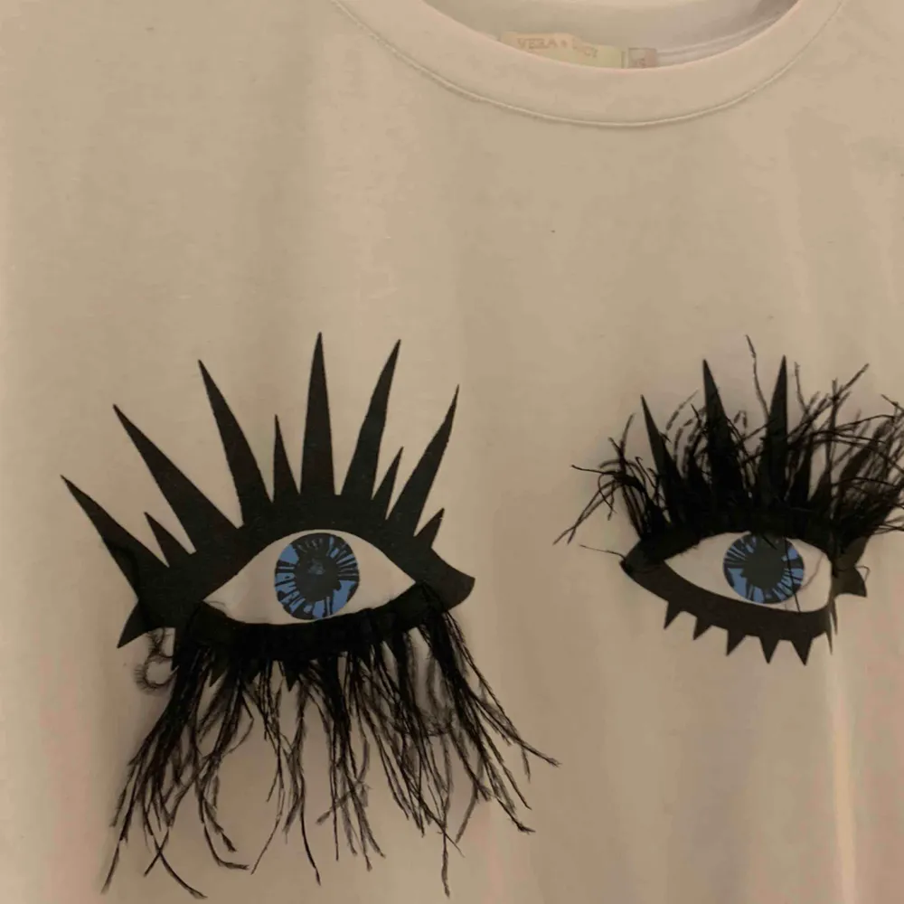 T-shirt med ögon och fjäderfransar Köpt i butik i Frankrike! Använt 2 ggr.  Funkar toppen för mig som har strl S😊. T-shirts.