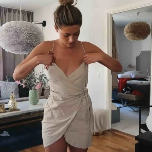  - Beige omlottklänning från Kristin Sundberg x NA-KD. Helt oanvänd i storlek 38 (liten i storleken mer som en 36:a). Utsåld modell