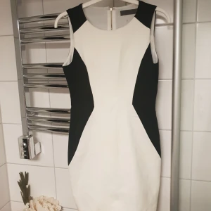  - Jättefin vit/svart figursydd klänning med dragkedja i mässing längst hela ryggen. Går ungefär till ovanför knäna. Bra skick! Använd 2 gånger.  Frakt tillkommer💕