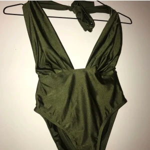 Baddräkt  - Militärgrön baddräkt med ett band över midjan som man kan ha både fram och bak. Andra o tredje bilden är lånade.