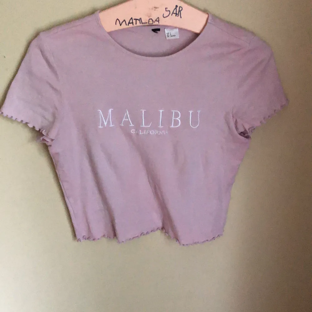 Supersöt lila topp från H%M, croppad med trycket MALIBU California. Volang på både ärmar och nertill. T-shirts.