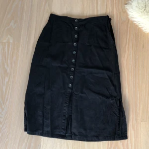 Kjol med knappar - Kjol med knappar och öppning vid sidan. Slits på vardera sida om benet ca 20 cm