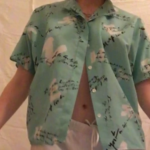 Skjorta  - En turkos skjorta med tryck, med följande skärp