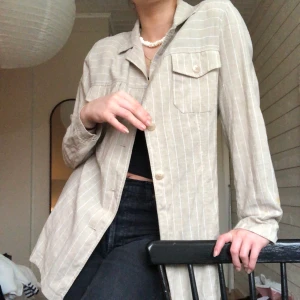 Skjorta/kavaj/overshirt i linne - Skjorta/kavaj/overshirt i linne (16%) köpt second hand. Beige med tunna vit ränder. Den har axelvaddar, men går att klippas bort om man inte skulle vilja ha dem. 