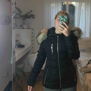 Hollies jacka  - Köptes för ca 1800kr, använd en vinter, i fint skick. Jackan är ifrån Hollies, märket roco baroco, i modellen Stocholm. Den har fuskpäls och två fickor på framsidan, plus en innerficka. 