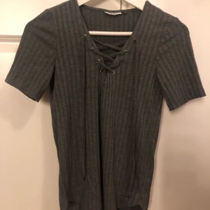 T-shirts från Only  - En fin t-shirts från Only använd ganska många gånger drf säljs tröjan ändast för 50 kr. Tröjan är mörk grå med snörning över brösten.