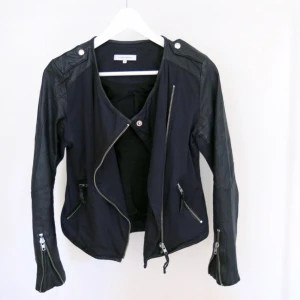  - Skinnjacka från Second Female inköpt för ett år sedan för 1699kr. Använd ett fåtal gånger. Jackan är i mörkblått, nästan svart tyg med skinndetaljer men ger känslan av en skinnjacka! 💙💎 frakt 49kr. Jag har svisch! 