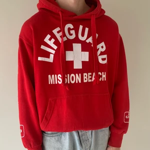 Röd LIFEGUARD hoodie  - Säljer denna röda Lifeguard hoodie i storlek S, men passar mer XS/S. Fint skick, dock en liten slitning på ärmudden men det är inget som märks, se bild. Spårbar frakt tillkommer på 63kr.