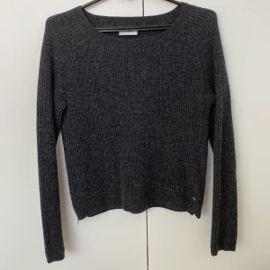 Stickad tröja med dragkedjor - Säljer denna stickade tröja från Boomerang eftersom den inte används längre. Tröjan är mörkgrå med dragkedje-detaljer på vardera sida. Varm och mysig. 