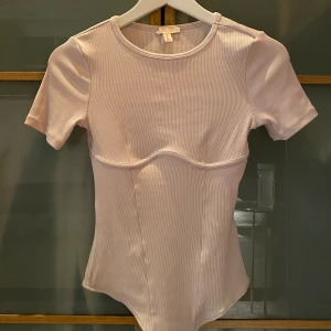 H&M body - Krämvit body från H&M. Bygel imiterad under brösten. Sitter tight men bekvämt.