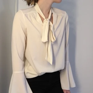  - Galet fin blus från Warehouse! 🤩 Knappt använd, så i toppenskick! 🌸 Färgen är lite åt det eggshell-vita hållet! ⚡️ Knytning framför en djupare v-ringning och stora trumpetärmar! 🦋 Kan skickas, men då står köpare för frakt! 💌 Katt finns i hemmet! 🐈