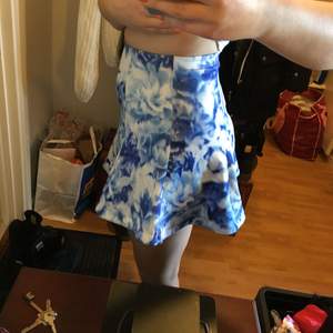 Blommig, blå-vit kjol från bikbok i lätt scuba-material. Dragkedja bak. Frakt 45kr.