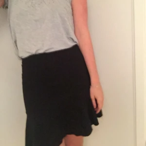  - Stretchig kjol med volangkant nertill, passar lika bra till strumpbyxor som barbent.