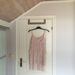  - Skicket på klänningen är bra men den skulle behöva en strykning efter att ha hängt ett tag i garderoben. Klänningen är "stel" och jag skulle säga att det är en mindre 38. Den är i ljust rosa men något mörkare än vad bilderna visar.