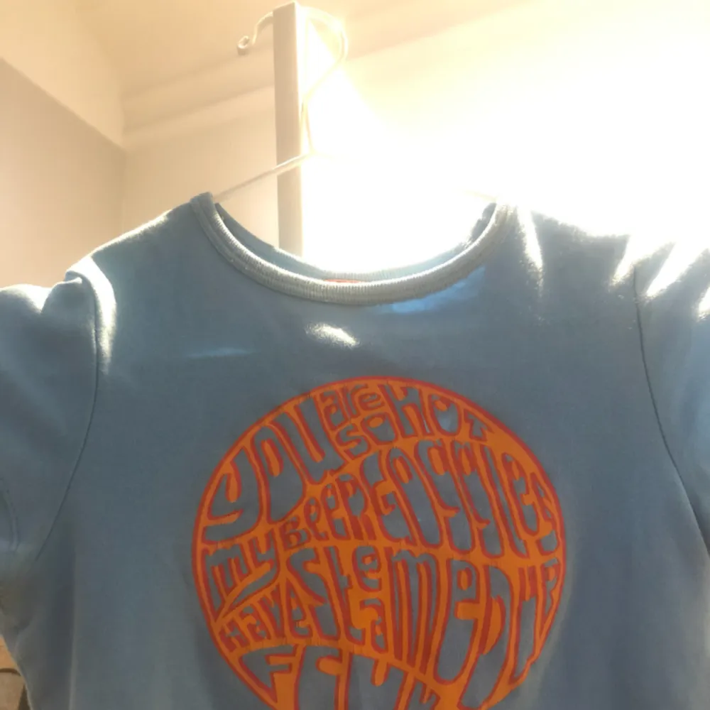 blå 70-tals t-shirt med oranget tryck, knappt använd:-) superfin nu till vår/sommar! frakten kostar 30 kr. T-shirts.