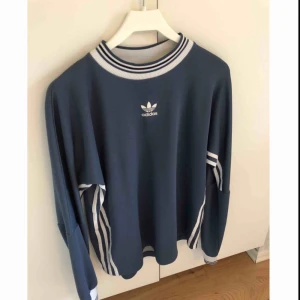  - Tjockare långärmad tröja ifrån Adidas. Herrstorlek S men sitter snyggt oversize om man knyter upp den. Köpt ifrån Plick tidigare men säljes nu för den inte kommer till användning längre. Bra skick. Frakt betalar köpare. 