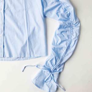 Oanvänd skjorta från Missguided. Åtdragbara ärmar med knytning. Ljusblå och vit-randig. 