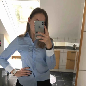  - Blå skjorta. Figursydd. Aldrig använd, lappen sitter fortfarande kvar. Bra kvalité i toppskick. Frakt tillkommer.