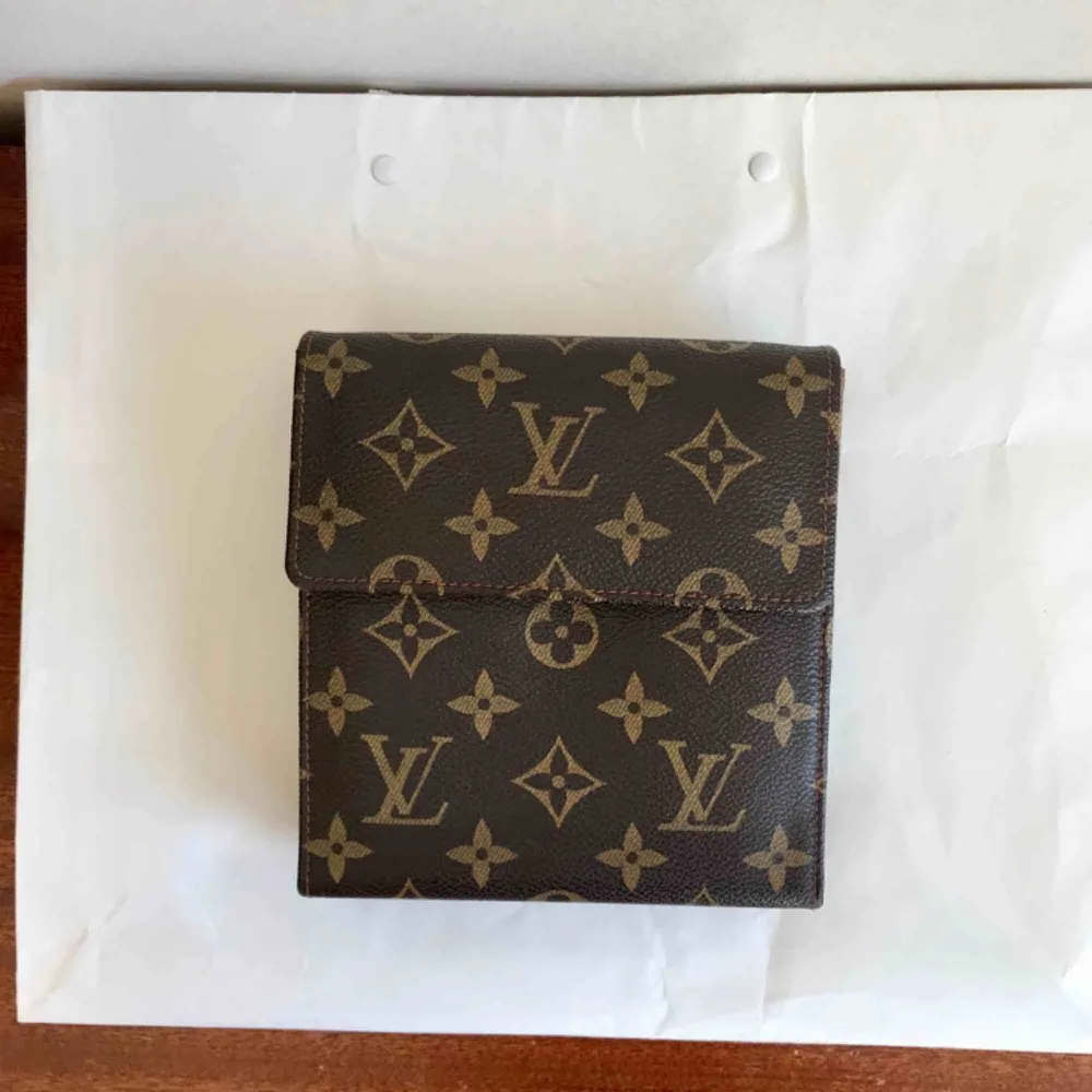 En fejk Louis Vuitton som utfällbar miniväska! Perfekt på krogen eller att använda som resefack där du kan förvara pass, kort, biljetter, mynt m.m. Finns även öglor så du kan fästa kedja eller smalare rem till.   Frakt ingår i priset!. Väskor.