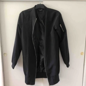  - En lång bomberjacka. Använt en gång. Materialet är lite likt mocka.  Köparen står för frakten (frakt ingår ej)