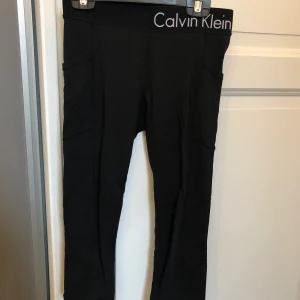 Calvin Klein träningsbyxor - Svarta trekvarts träningsbyxor från Calvin Klein i storlek XS säljes. Har fickor på sidan och är stretchiga. Väldigt sköna att ha på sig och är i väldigt fint skick, inte mycket använda.               