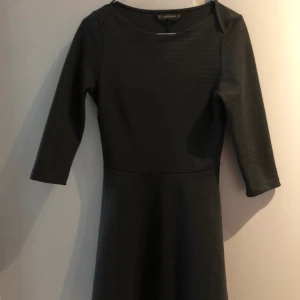 Svart kort klänning  - Svart klänning som är tightare i midjan och går ut vid kjolen. Halvlånga ärmar. Väldigt gott skick!