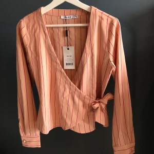 Rosa randigt sätt. - Ett rosa sätt med mörkrosa ränder. Tröjan har prislappen kvar, byxorna är heller aldrig använda men prislappen är avtagen där. Byxorna är i storlek 32 men väldigt vida och långa så passar för en större storlek.