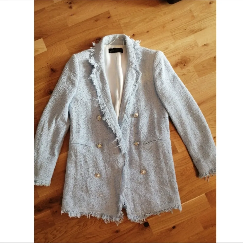 Zara ljusblå tweed-blazer med pärlknappar. Inköpt för 799kr. På bild 3 så finns det mellan bröstet och axeln på höger sida en ljusare färg på tyget, syns inte mycket men vill informera och därav det billiga priset ❤️. Kostymer.