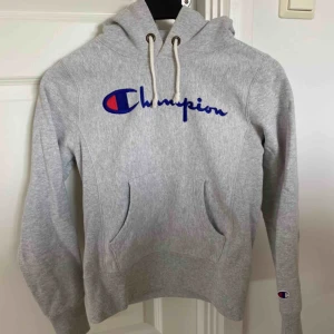  - Grå Hoodie/huvtröja från Champion med ficka på magen och ribbstickade muddar. Använd en gång.