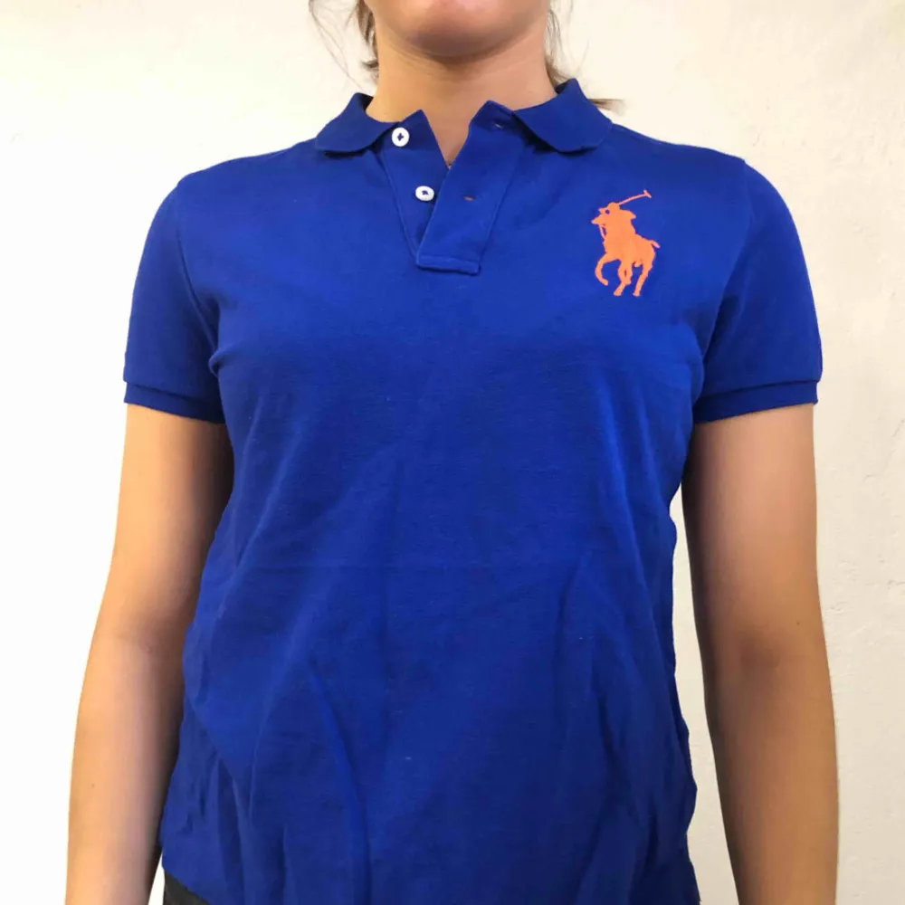 Mörkblå Ralphlaurenpolo med orange logga. Frakt ingår! Prutbart vid snabb och smidig affär. . T-shirts.