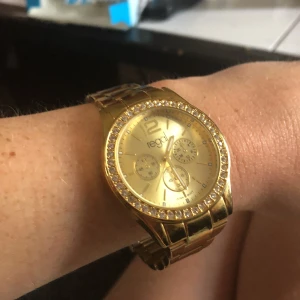 Guldig klocka - Guldig klocka med silver stenar runt klockan . Fint skicka och hel och fin . Dock måste batteri bytas därav priset . 💓