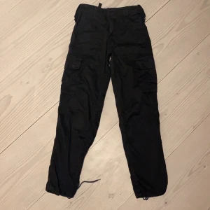 Cargo pants  - Svarta cargo panta, man kan justera passformen vid midjan och anklarna, högmidjade, strl M men funkar för S, jag vet att det var dåligt ljus på bilden men det är bara vanliga svarta cargo pants med fickor runt midjan och på rumpan