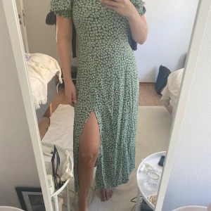En grön sommarklänning  - Aldrig använd sommarklänning. Grön med små blommor. Faller väldigt fint. Köparen står för frakten (ca 44-50kr).