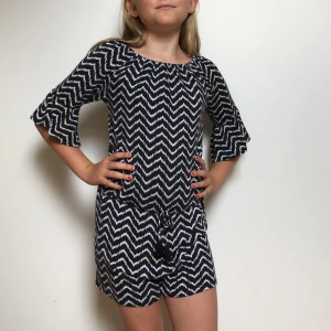 Rutig byxdress - Svart och vit byxdress med en rosett vid midjan. (Den slutar vid låren)