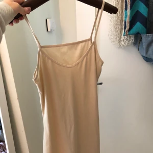 Klänning  - Tajt klänning i en beige rosa färg i stretchigt silkes tyg.