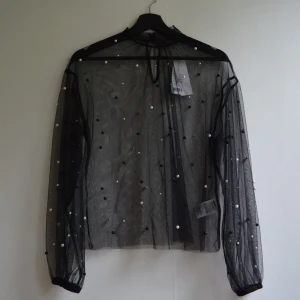 Blus i mesh - En svart långärmat blus i mesh. Över tycket finns fastsydda pärlor som gör tröjan jättecool, snygg o unik. Köptes i höstas från Gina Tricot men aldrig använd. Prislappen sitter kvar. Därför jag säljer. Frakt 22kr 💕
