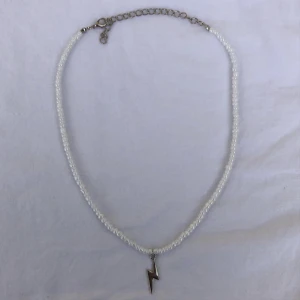 Halsband  - Halsband gjort med vita glaspärlor och en blixtberlock ⚡️🤍  Längsta längd: 54 cm  Kortaste längd: 45 cm  Pris: 89 kr  Frakt: 11 kr  Kontakta mig vid intresse!  Bör ej komma i kontakt med vatten!  Instagram: Thelmassmycken 